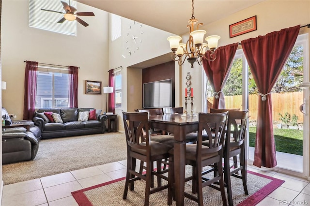 dining area with light tile patterned floors, a high ceiling, and ceiling fan with notable chandelier