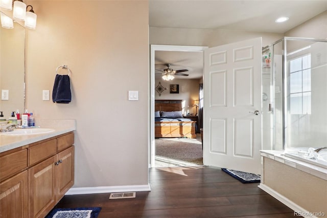 14389 E 101st Pl, Commerce City, CO 80022 - ensuite bathroom featuring vanity, wood finished floors, a ceiling fan, a stall shower, and a garden tub