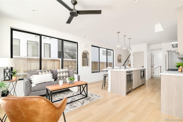 living room with sink, light hardwood / wood-style floors, and ceiling fan