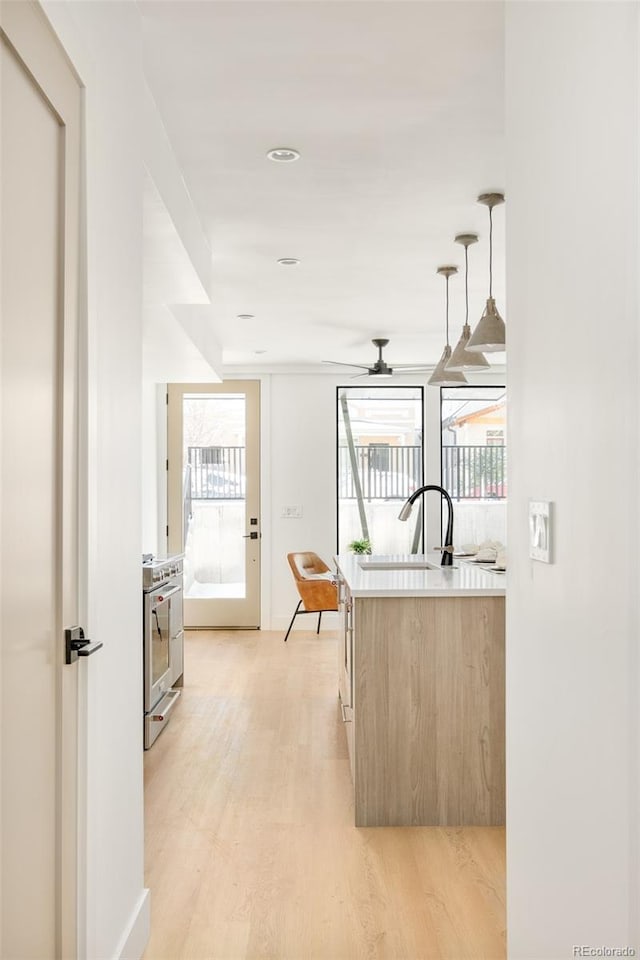 kitchen featuring pendant lighting, sink, high end stove, light hardwood / wood-style floors, and light brown cabinetry