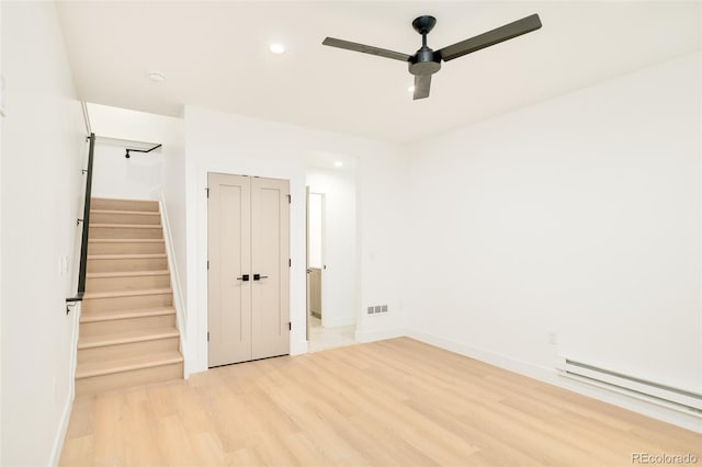 spare room featuring ceiling fan, a baseboard radiator, and light wood-type flooring