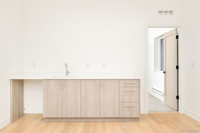 interior space with sink, hardwood / wood-style floors, and a baseboard heating unit