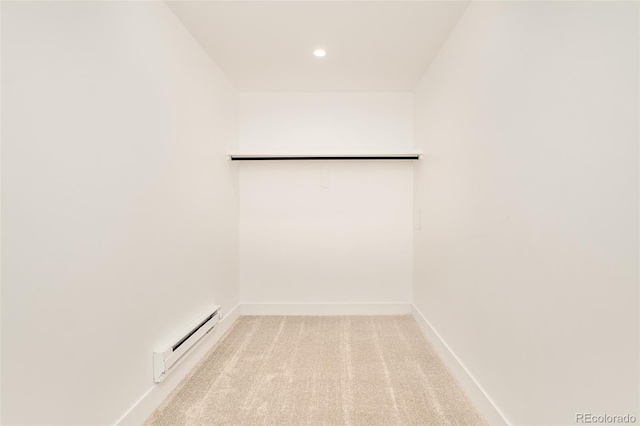 spacious closet featuring a baseboard radiator and light colored carpet