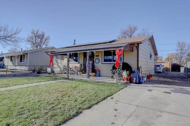 view of front facade featuring covered porch, solar panels, and a front lawn