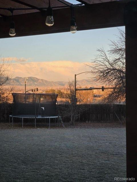 yard at dusk with a trampoline and a mountain view