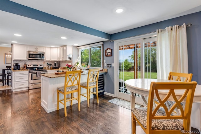 kitchen with dark hardwood / wood-style floors, kitchen peninsula, appliances with stainless steel finishes, and white cabinets