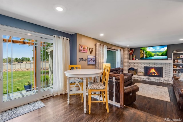 dining space featuring a brick fireplace and wood-type flooring