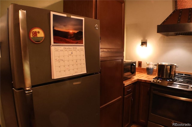 kitchen featuring stainless steel fridge, stove, dark brown cabinetry, extractor fan, and butcher block countertops