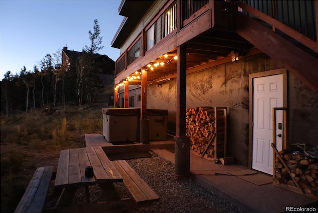 property exterior at dusk with a deck and a hot tub