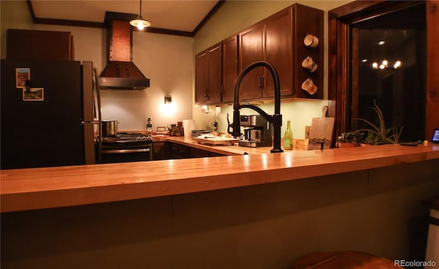 kitchen with black refrigerator, wooden counters, exhaust hood, pendant lighting, and range with gas stovetop