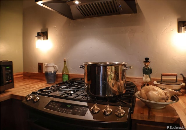 kitchen featuring gas stove, hardwood / wood-style flooring, and ventilation hood