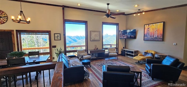 living room with ceiling fan with notable chandelier, a healthy amount of sunlight, wood-type flooring, and crown molding