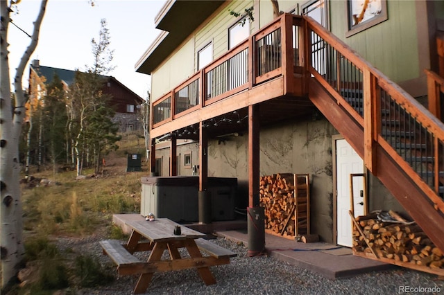 rear view of house with a hot tub and a wooden deck