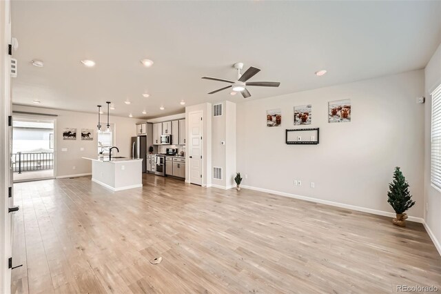 unfurnished living room featuring light wood finished floors, visible vents, baseboards, and ceiling fan