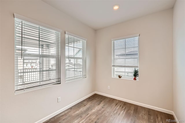 empty room featuring baseboards, recessed lighting, plenty of natural light, and wood finished floors