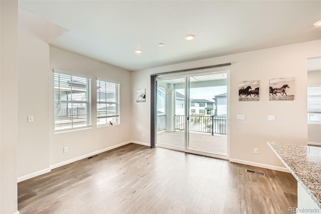 spare room with a wealth of natural light, baseboards, visible vents, and light wood-style floors