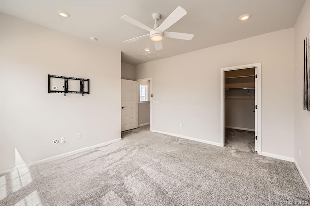 unfurnished bedroom featuring baseboards, a ceiling fan, carpet floors, and a walk in closet