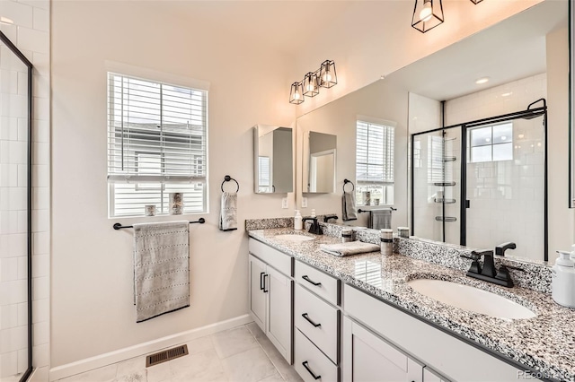 bathroom with a shower stall, baseboards, a healthy amount of sunlight, and a sink
