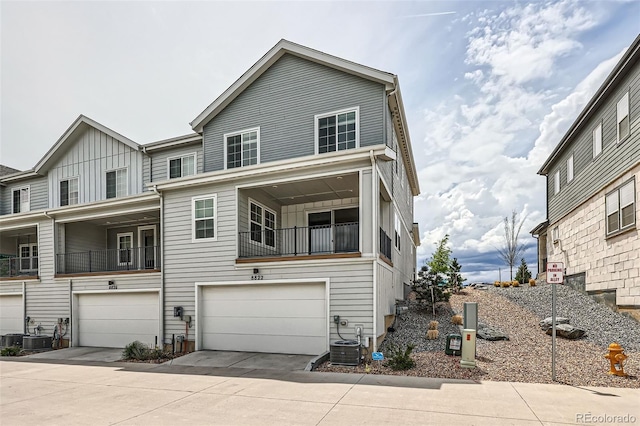 townhome / multi-family property featuring cooling unit, board and batten siding, driveway, and a garage