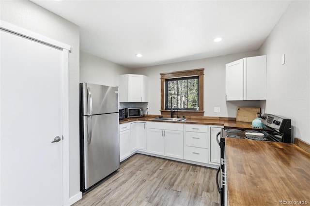 11390 Shimley Rd, Golden, CO 80403 - kitchen featuring appliances with stainless steel finishes, butcher block counters, a sink, white cabinetry, and light wood finished floors