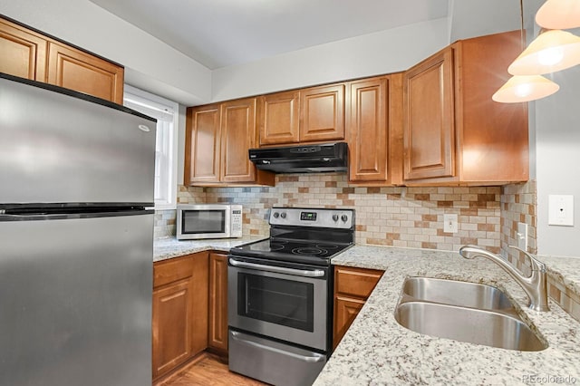3619 Queen Anne Way, Colorado Springs, CO 80917 - kitchen featuring stainless steel appliances, under cabinet range hood, a sink, brown cabinetry, and light stone countertops