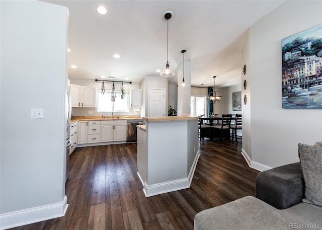 kitchen with white cabinetry, decorative light fixtures, dark hardwood / wood-style flooring, dishwasher, and kitchen peninsula