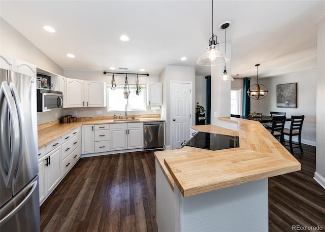 kitchen with pendant lighting, stainless steel appliances, sink, and white cabinets