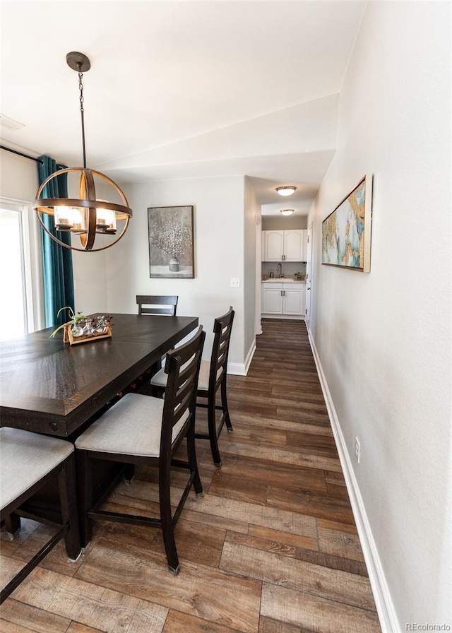 dining space with dark hardwood / wood-style flooring, sink, and a chandelier