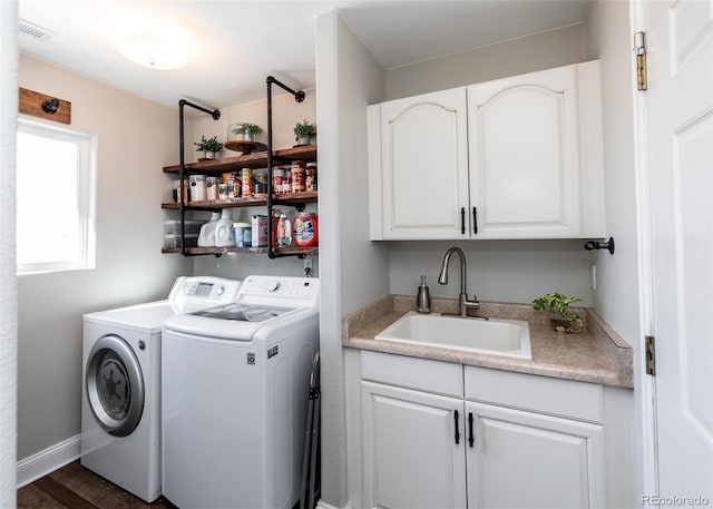 clothes washing area with dark wood-type flooring, cabinets, sink, and washing machine and dryer