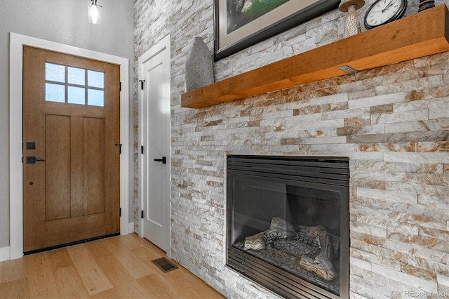 foyer featuring a stone fireplace and light wood-type flooring