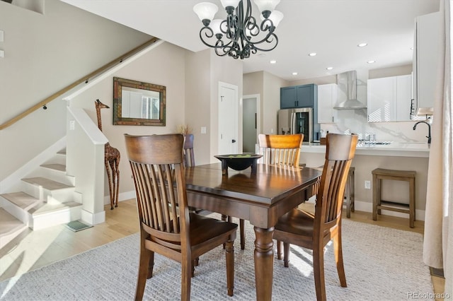 dining room featuring an inviting chandelier, sink, and light wood-type flooring