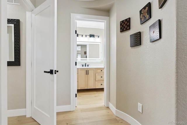 hall with sink and light hardwood / wood-style flooring