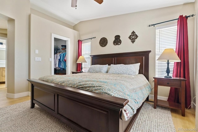 bedroom featuring lofted ceiling, a spacious closet, a closet, ceiling fan, and light hardwood / wood-style floors