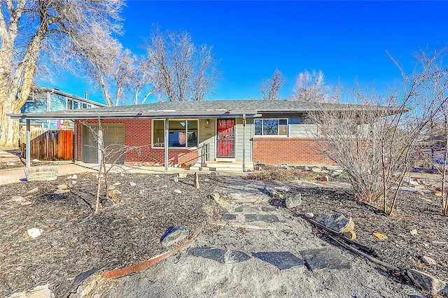 ranch-style house featuring a garage, brick siding, fence, and driveway