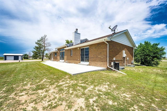 41020 US Highway 36, Bennett, CO 80102 - rear view of house featuring brick siding, a patio, a chimney, and a yard
