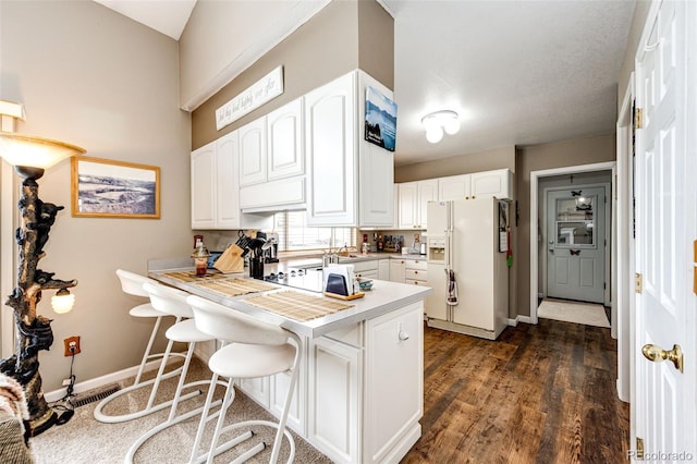 41020 US Highway 36, Bennett, CO 80102 - kitchen featuring white fridge with ice dispenser, a kitchen bar, a peninsula, white cabinets, and light countertops