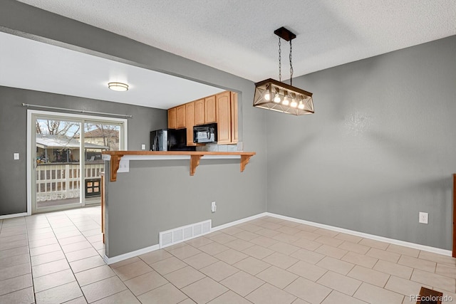 kitchen with a kitchen bar, kitchen peninsula, a textured ceiling, black appliances, and decorative light fixtures