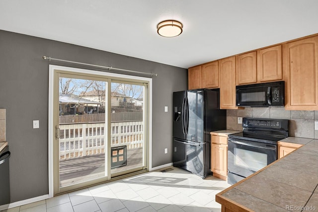 kitchen featuring tasteful backsplash, tile counters, and black appliances