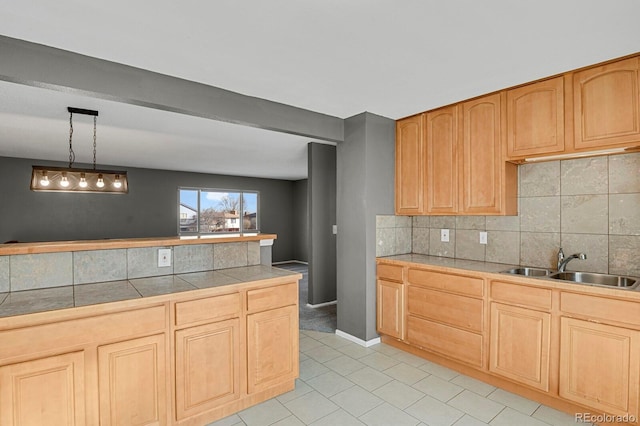 kitchen with decorative backsplash, sink, decorative light fixtures, and light brown cabinets