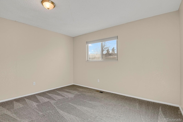 carpeted empty room featuring a textured ceiling