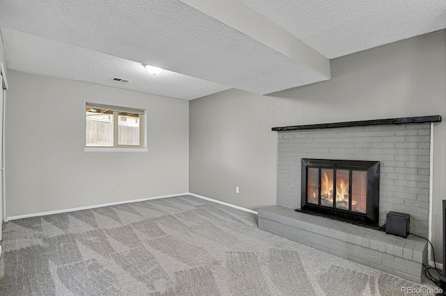 unfurnished living room featuring carpet, a textured ceiling, and a brick fireplace