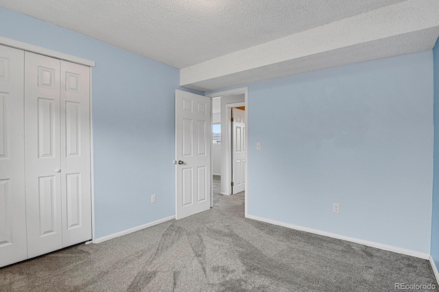 unfurnished bedroom with carpet, a textured ceiling, and a closet