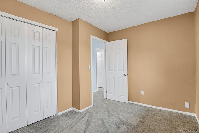 unfurnished bedroom featuring light colored carpet, a textured ceiling, and a closet