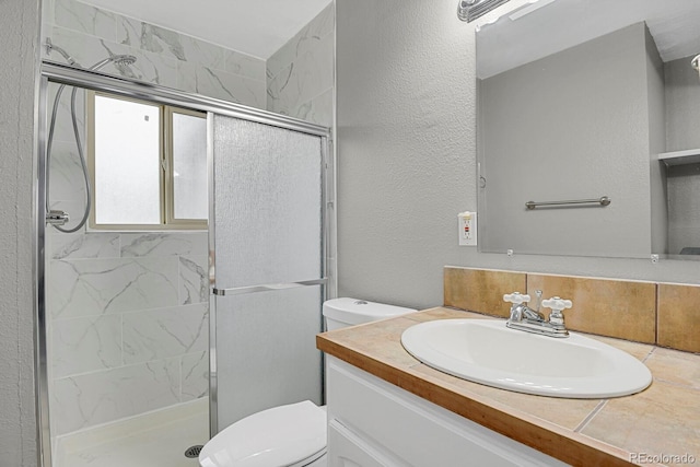 bathroom featuring vanity, toilet, and a shower with door