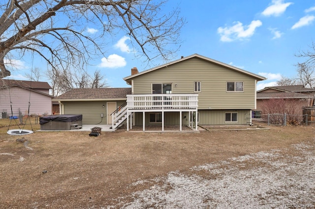 back of property with a hot tub and a deck