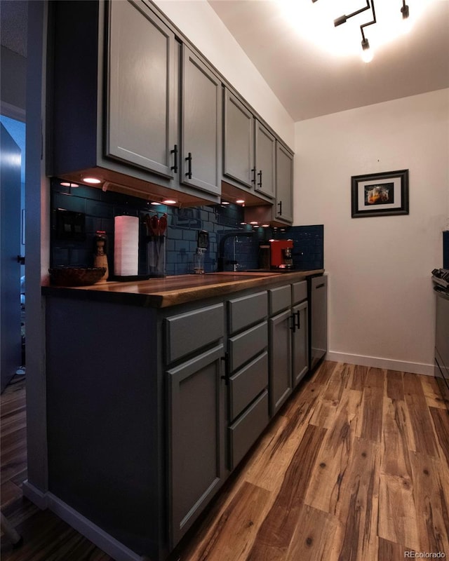 4110 Hale Pkwy Unit 5G, Denver, CO 80220 - kitchen with gray cabinetry, dark countertops, decorative backsplash, and wood finished floors