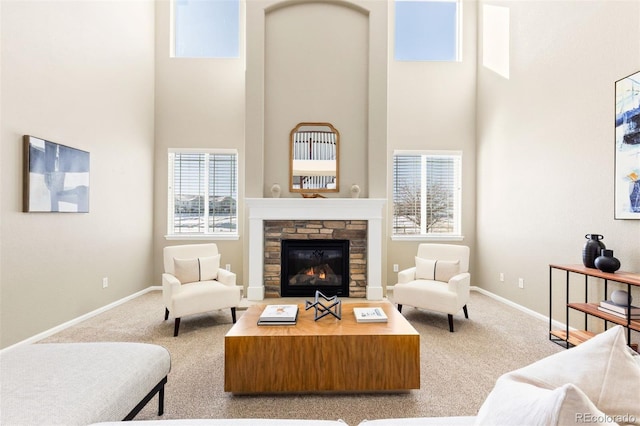 carpeted living room with a towering ceiling and a stone fireplace