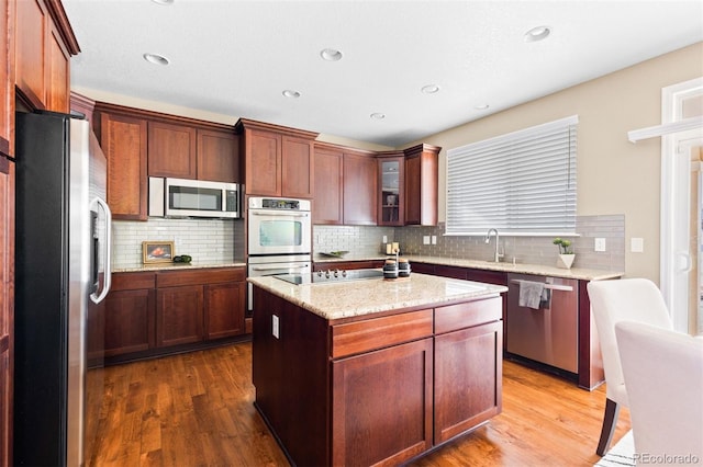 kitchen featuring a kitchen island, stainless steel appliances, hardwood / wood-style flooring, and tasteful backsplash