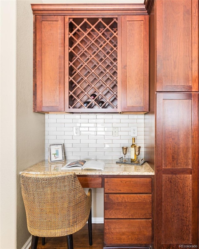 bar with light stone countertops, backsplash, and hardwood / wood-style flooring