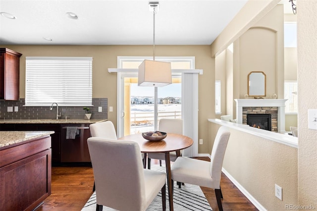 dining space with dark wood-type flooring, a wealth of natural light, and a fireplace